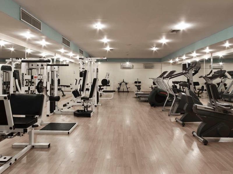 Gran gimnasio moderno con varias máquinas de ejercicio y luces brillantes.