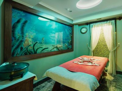 Stanza per trattamenti con lettino da massaggio e murale subacqueo nell'area spa.