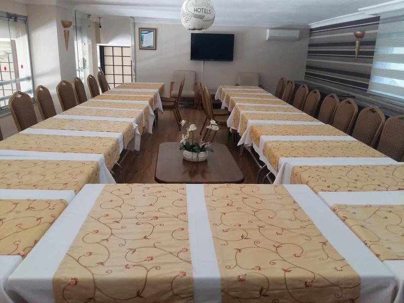 Sala conferenze con disposizione a tavolo a U e sedie marroni, decorazione neutra.