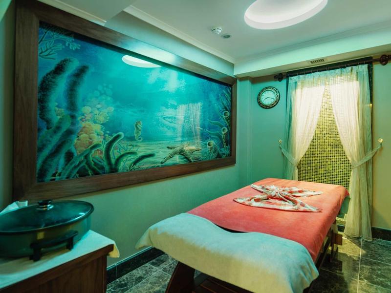 Stanza per trattamenti con lettino da massaggio e murale subacqueo nell'area spa.