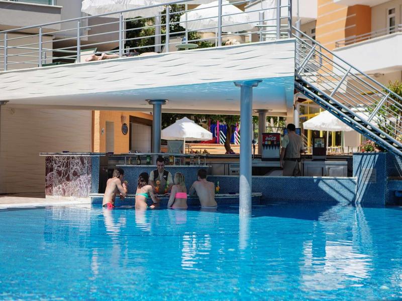 Piscina dell'hotel con swim-up bar e ospiti seduti in acqua che gustano bevande.