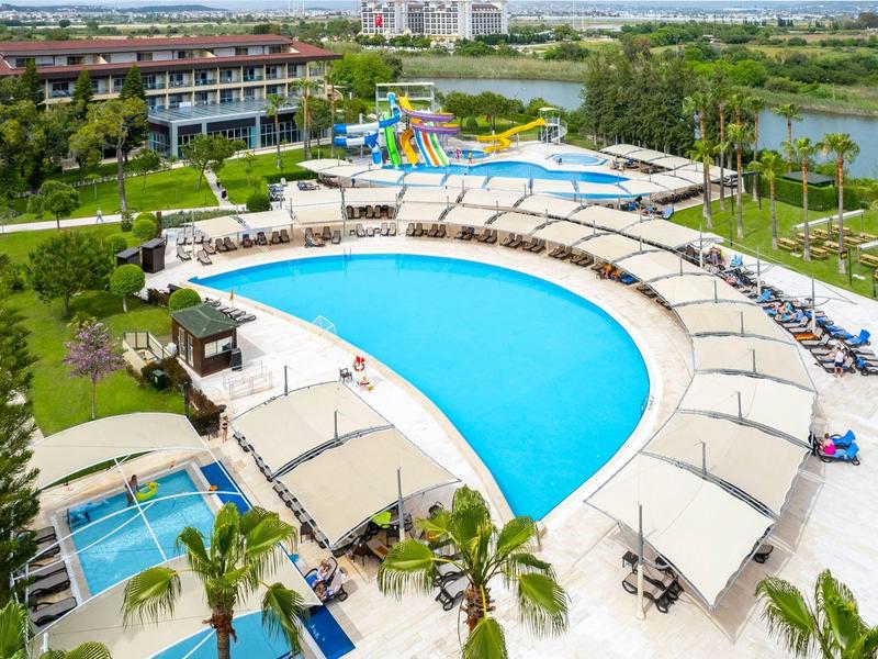 Gran piscina curva con toboganes y varias piscinas más pequeñas en un complejo turístico junto al lago