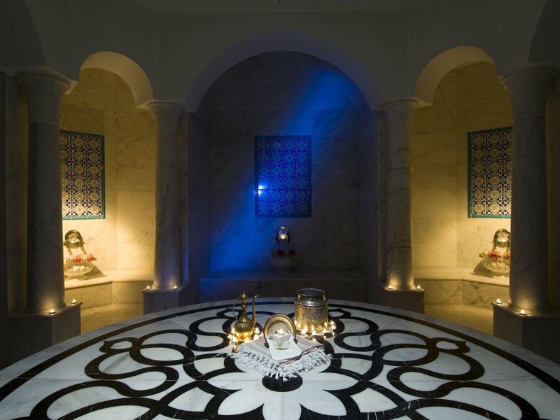 Mesa elegante con velas y copas en una sala con iluminación ambiental y arcos.