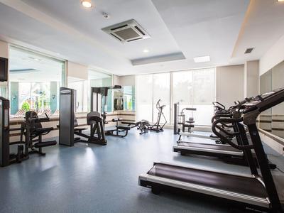 Großer Fitnessraum mit Laufbändern, Fahrrädern und Hanteln, heller Raum mit Fenstern und Spiegeln.