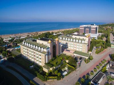 Großes Hotelgelände mit mehreren Gebäuden, Grünflächen und Blick auf Strand und Meer bei klarem Himmel.