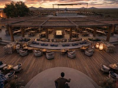 Bar en plein air accueillante avec mobilier en bois et ambiance au coucher du soleil.