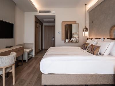 Habitación de hotel moderna con cama doble, escritorio, silla y espejo grande.