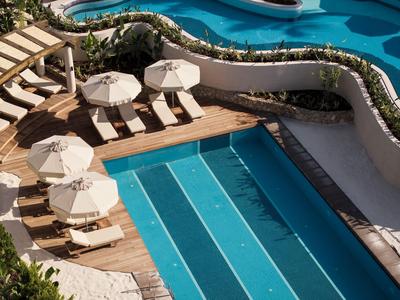 Piscina exterior moderna con tumbonas y sombrillas en terraza de madera en hotel.