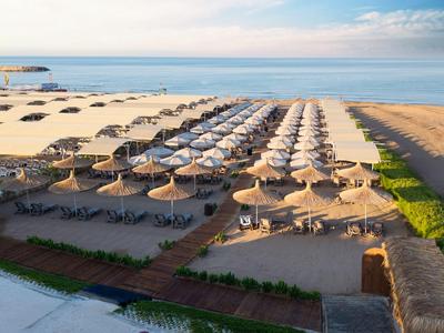 Spiaggia con file di ombrelloni e lettini lungo il mare.