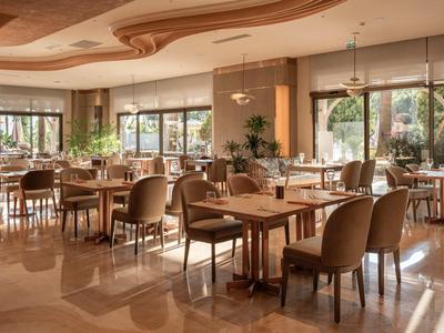 Ristorante luminoso e moderno con grandi finestre, tavoli in legno e sedie comode.