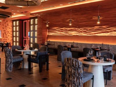 Ristorante moderno con tavoli eleganti, sedie e pareti illuminate caldamente.