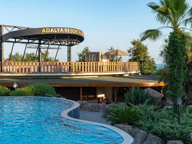 Strefa basenu w ośrodku z palmami i barem na zewnątrz pod czystym niebem.