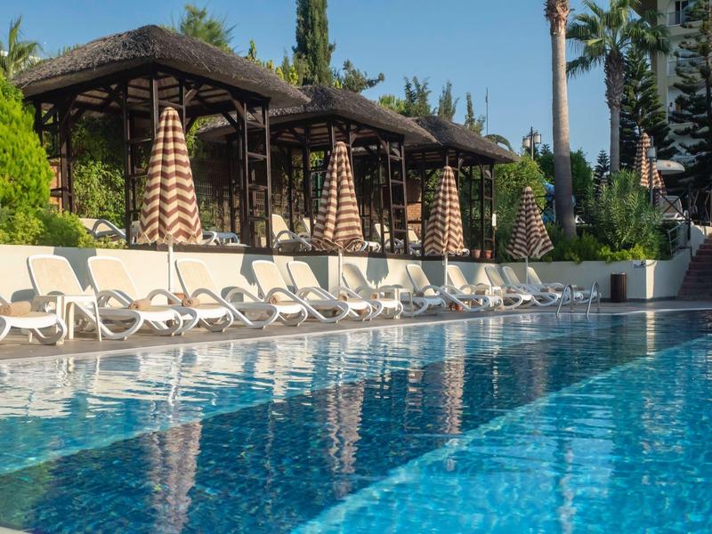 Czysty basen z leżakami i parasolami w tropikalnym ogrodzie.