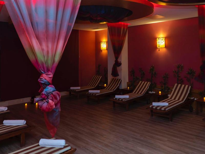 Przytulne miejsce spa z leżakami, przyciemnionym światłem i dekoracyjną zasłoną.