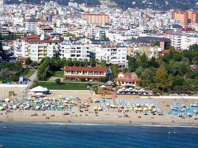 Plage avec transats et parasols devant une ville avec de nombreux bâtiments.