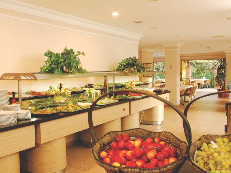 Buffet avec différents plats et un panier de fruits dans une salle à manger lumineuse.