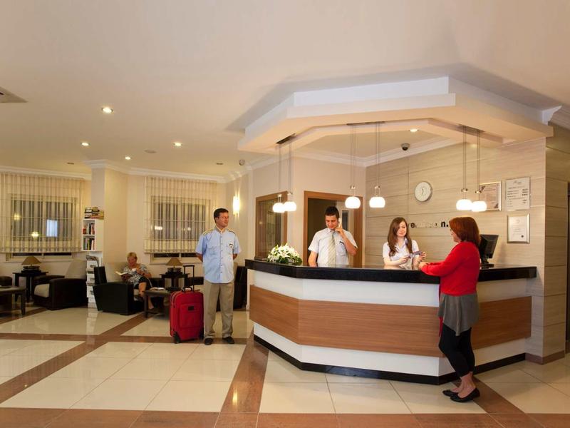 Réception d'hôtel avec clients et personnel, intérieur chaleureux éclairé et bagages