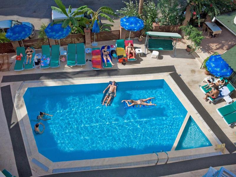 Vue sur une piscine avec des personnes se détendant sur des matelas gonflables et nageant.