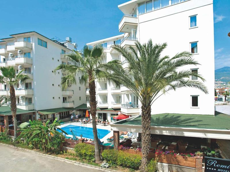 Bâtiment d'hôtel avec piscine et palmiers sous un ciel bleu clair