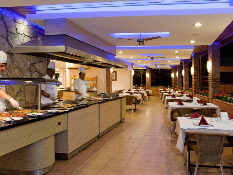 Restaurant moderne avec buffet, longues tables et éclairage élégant.