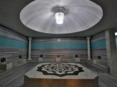 Innenraum eines türkischen Hamams mit zentralem Marmorwaschbecken und umlaufenden Sitzen.