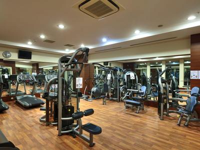 Heller Fitnessraum mit verschiedenen Sportgeräten und Holzfußboden.