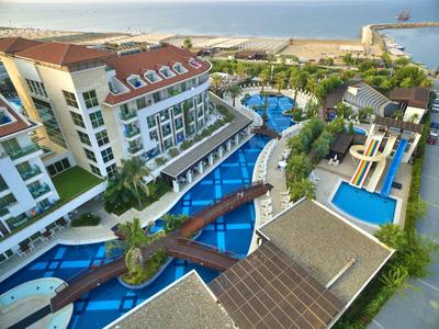 Luxurious hotel with a large pool, water slides, bridges, and a sea view.