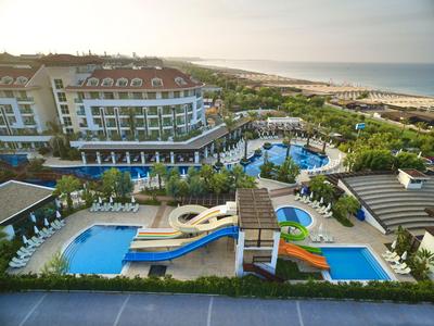 Hotel complex with multiple pools, water slides, and sun loungers by the sea