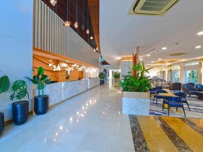 Bright hotel lobby with marble floor, plants, and modern seating area.