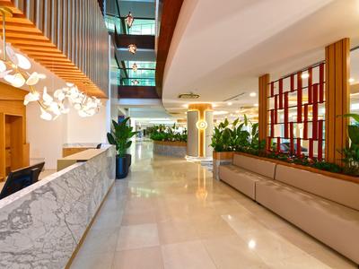 Bright hotel lobby with modern reception, plants, and stylish seating areas.