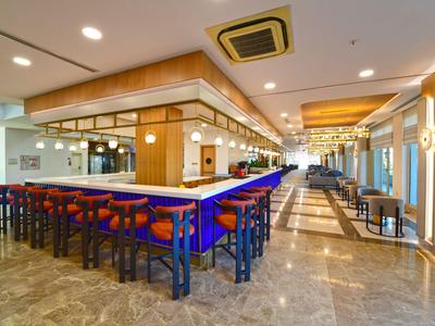 Modern hotel bar area with high counter and seating on marble flooring.