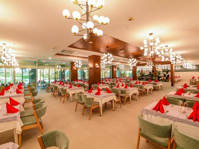 Large hotel dining room with tables, red folded napkins, and modern chandeliers.