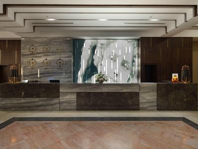 Moderne Hotelrezeption mit dunklen Marmorfronten, Holzwänden und Kunstwerk hinter dem Tresen.