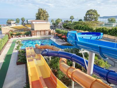 Ein Wasserpark mit mehreren bunten Rutschen, Schwimmbecken und grüner Umgebung am Meer.