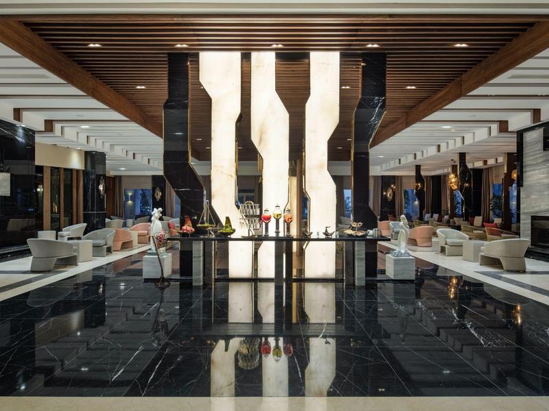 Nowoczesne i eleganckie wnętrze holu hotelowego z dużym żyrandolem i czarną marmurową podłogą.