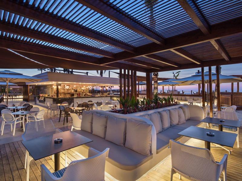 Taras hotelowy z sofami i stolikami o zmierzchu, ciepła i nowoczesna atmosfera.