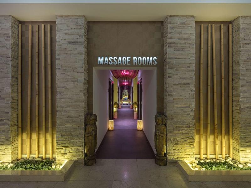 Eleganckie wejście do pokoi masażu oświetlone ciepłym światłem przy ziemi.