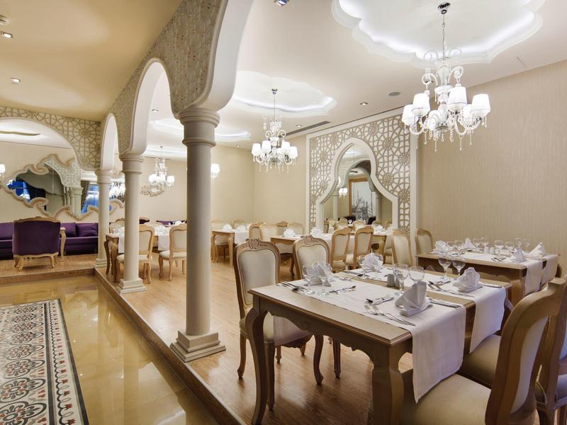 Elegancka jadalnia z łukami, żyrandolami i nakrytymi stołami, wyrafinowany klimat.