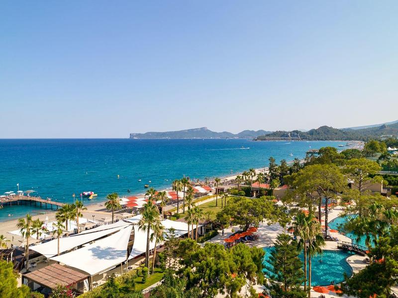 Tętniąca życiem plaża z parasolami, basenem i niebieskim morzem pod czystym niebem.