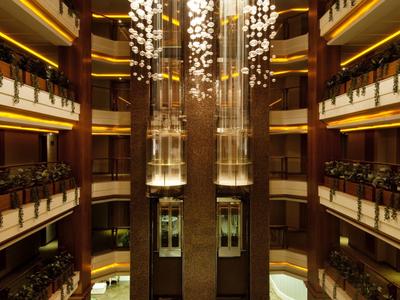 Luxusní hotelové interiéry s několika patry a velkými skleněnými výtahy uprostřed.