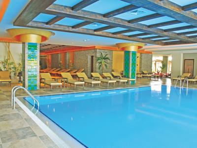 Vnitřní bazén s lehátky a velkou skleněnou střechou v hotelu