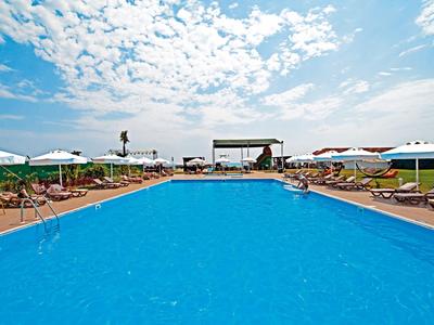 Large outdoor pool with loungers and umbrellas under blue sky
