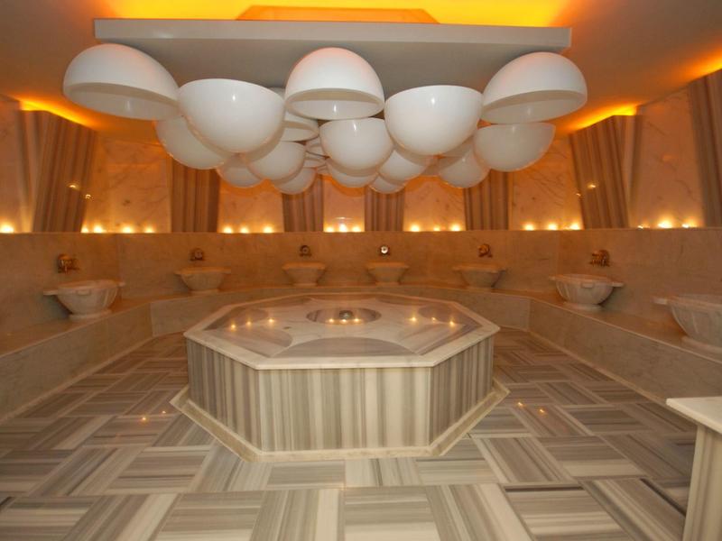 Moderní hammam s centrální nádrží na vodu, lavicemi a unikátním stropním osvětlením.