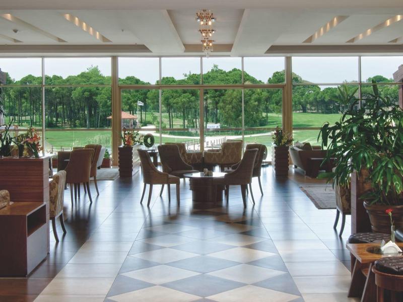 Světle zařízená jídelna s okny od podlahy ke stropu a výhledem na zahradu.