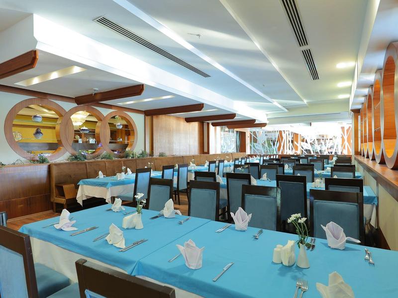 Světla restaurace s modrými ubrusy, pečlivě složenými ubrousky a moderními dřevěnými prvky.