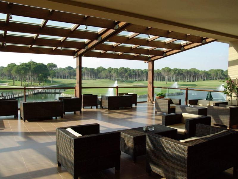 Zastřešená terasa s moderním posezením a výhledem na vodu a zelenou krajinu.