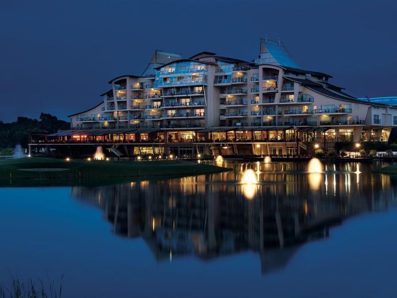 Moderní hotelová budova osvětlená v noci u vody s odrazy
