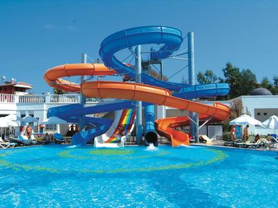 Barevné tobogány nad velkým modrým bazénem v slunném hotelovém resortu.