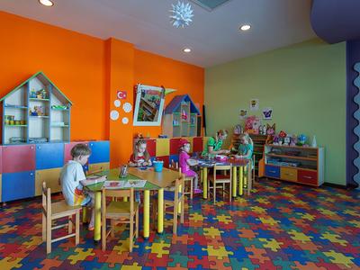 Barevná herna pro děti s stoly, židlemi a hračkami v hotelu.