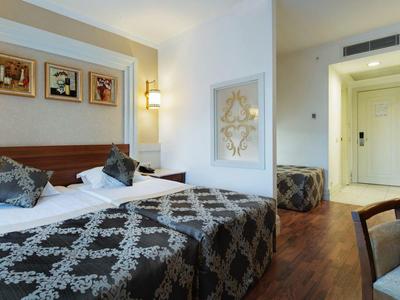 Světý hotelový pokoj s manželskou postelí, psacím stolem a moderním dekorem.